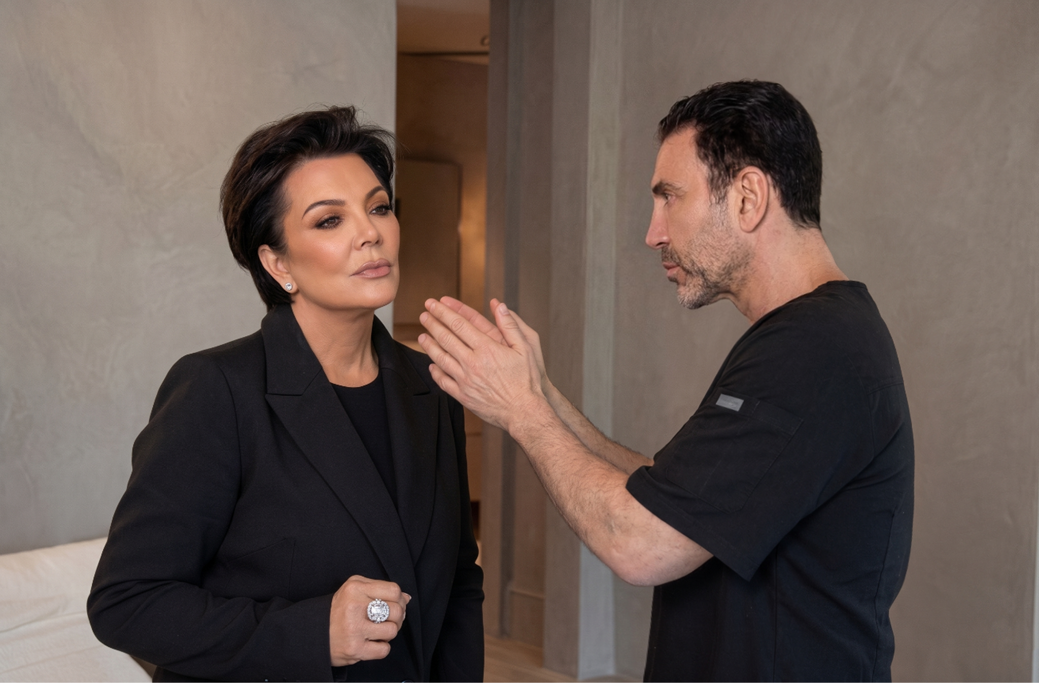 Photo of woman listening as cosmetic surgeon gestures toward her face