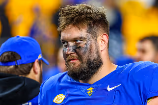 Football player with face paint in blue jersey looking to the side during a game.