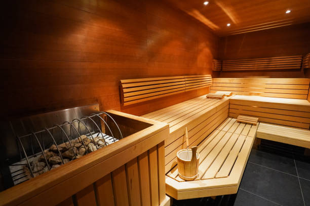 Interior of a wooden sauna with benches, a bucket, and heated stones for steam.