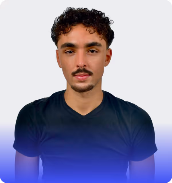 Der Webdesign Experte Faris Schmidt mit lockigem Haar und Schnurrbart, bekleidet mit einem schwarzen T-Shirt, Webflow-Experte für B2B-Webdesign.