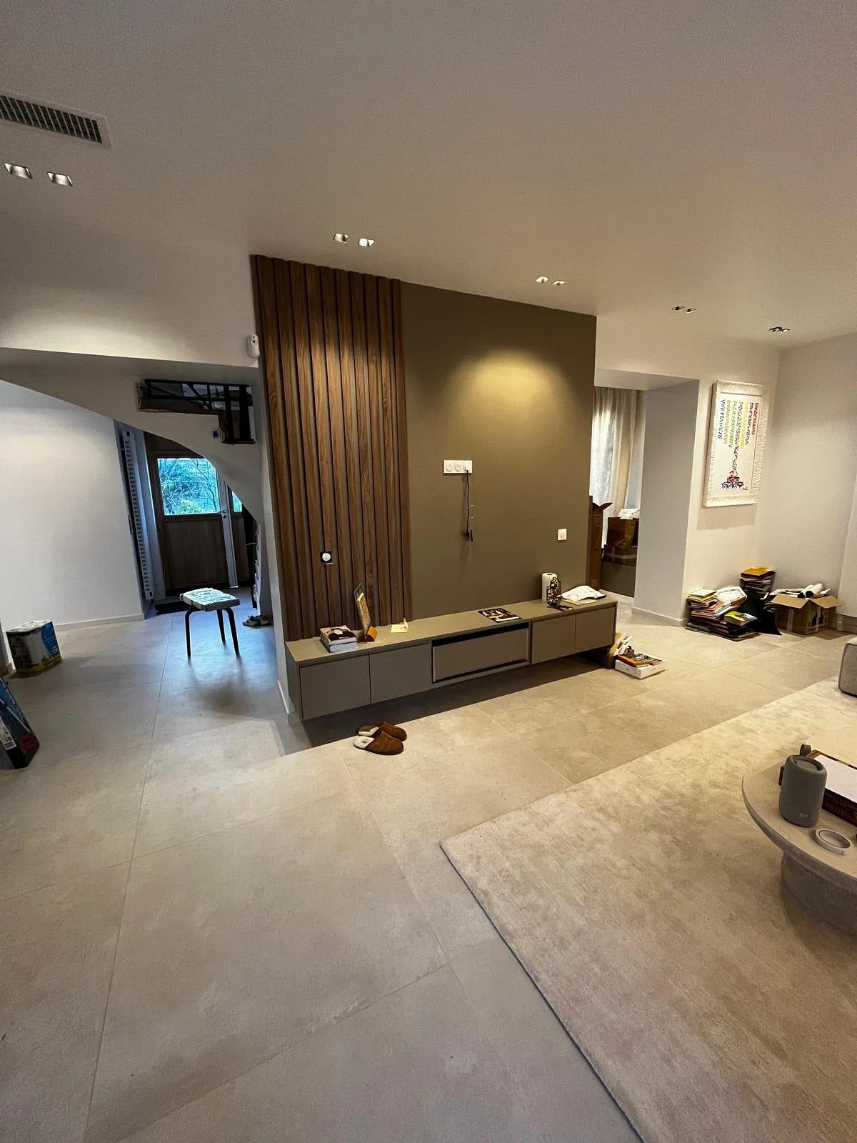 Intérieur moderne avec un mur décoratif en bois, un meuble TV suspendu, un tapis beige et une table basse ronde.