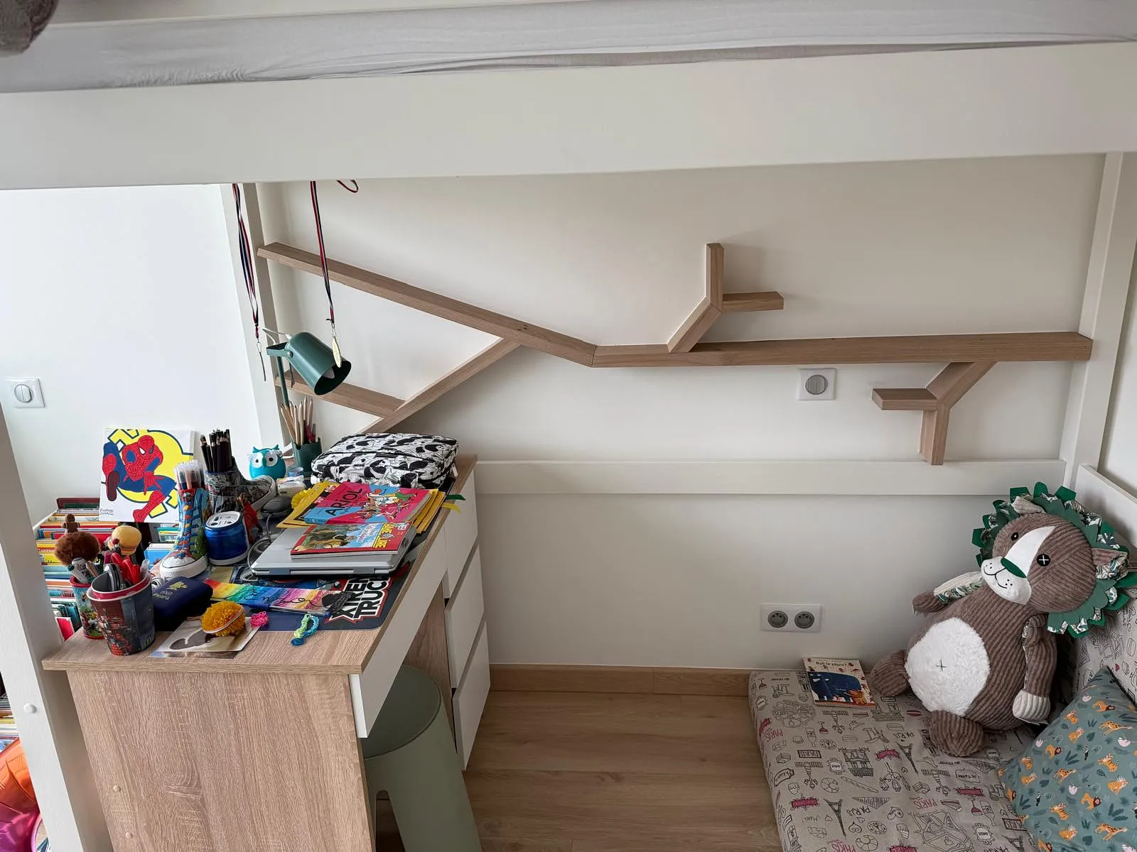 Coin bureau enfant avec dessin animé Spider-Man, livres, peluche lion et étagère murale en forme de branches.