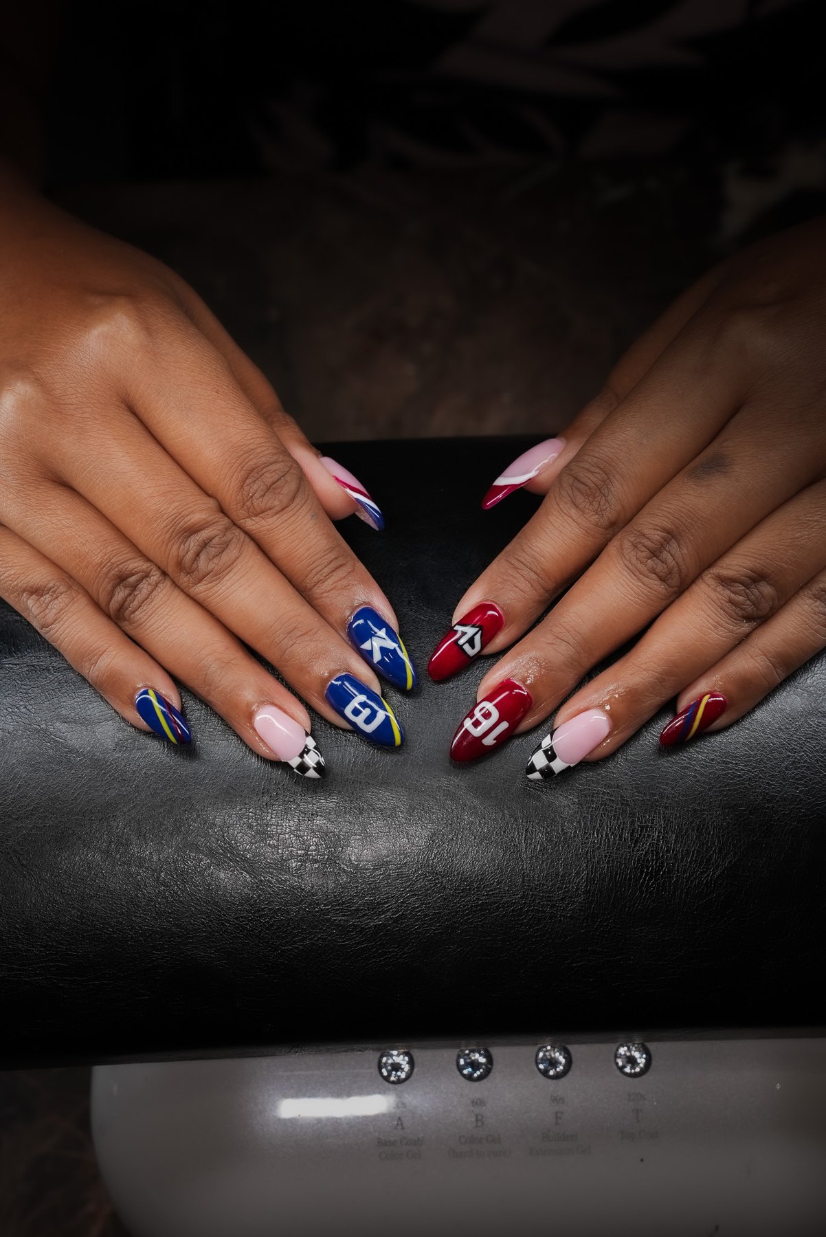 F1 nail art in Dubai: full set of navy and burgundy race livery nails with chequered flag tips at March14 Beauty Residence