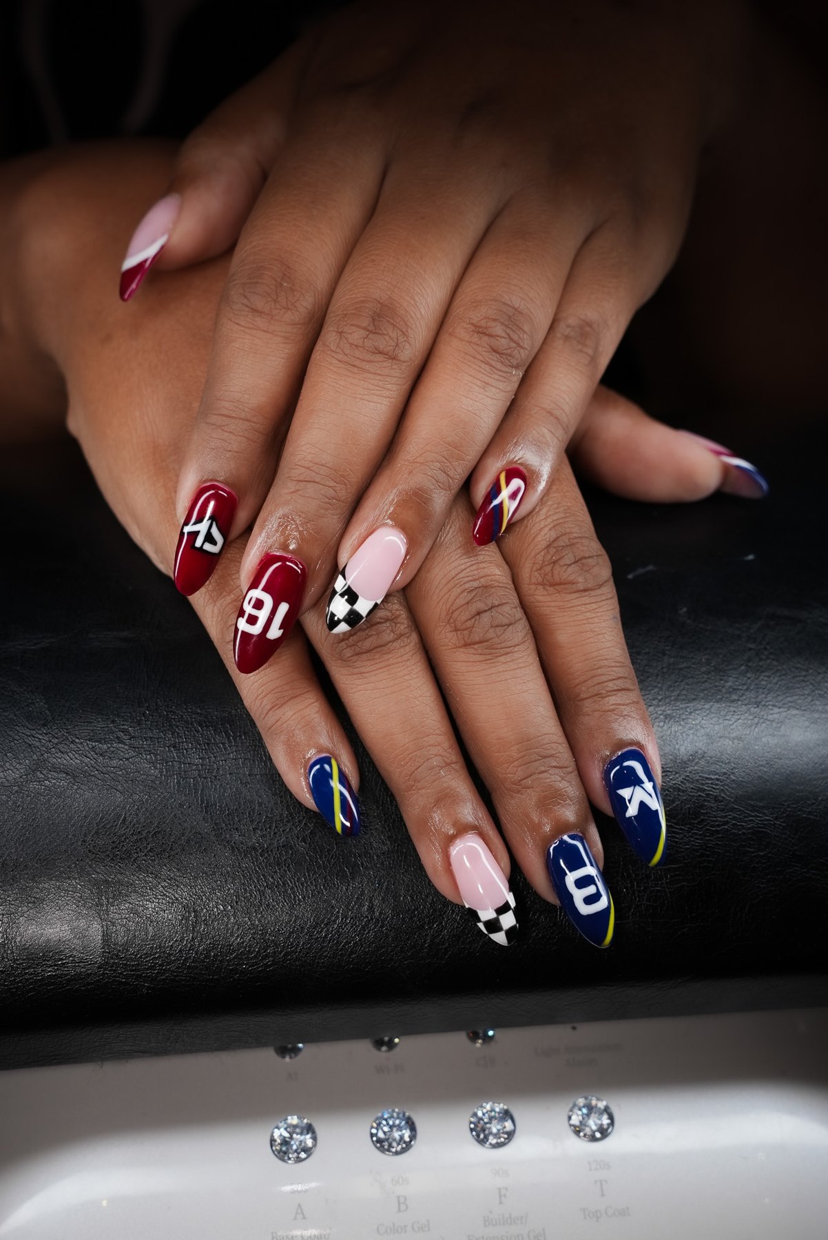 Both hands of the March14 F1 nail art set in Dubai, navy and burgundy liveries with race numbers and chequered tips