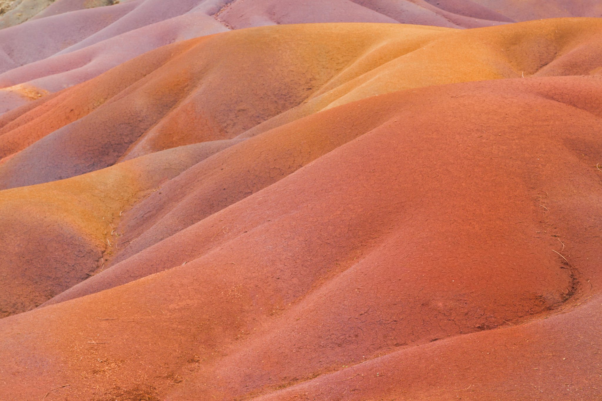 Smooth sand dunes with a gradient of colors ranging from reddish-orange to purple hues.