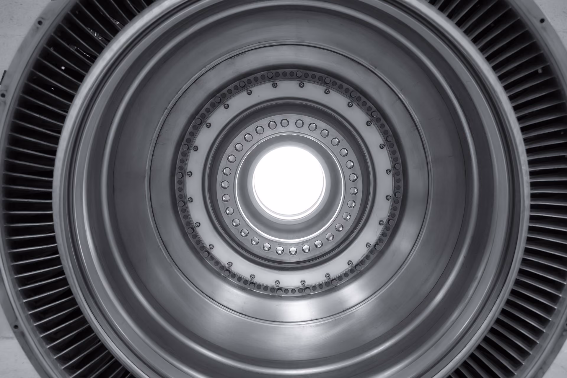 Close-up view looking inside a circular metallic turbine or jet engine component with blades around the edge, photo shoot in the shop of Advanced Turbine Systems