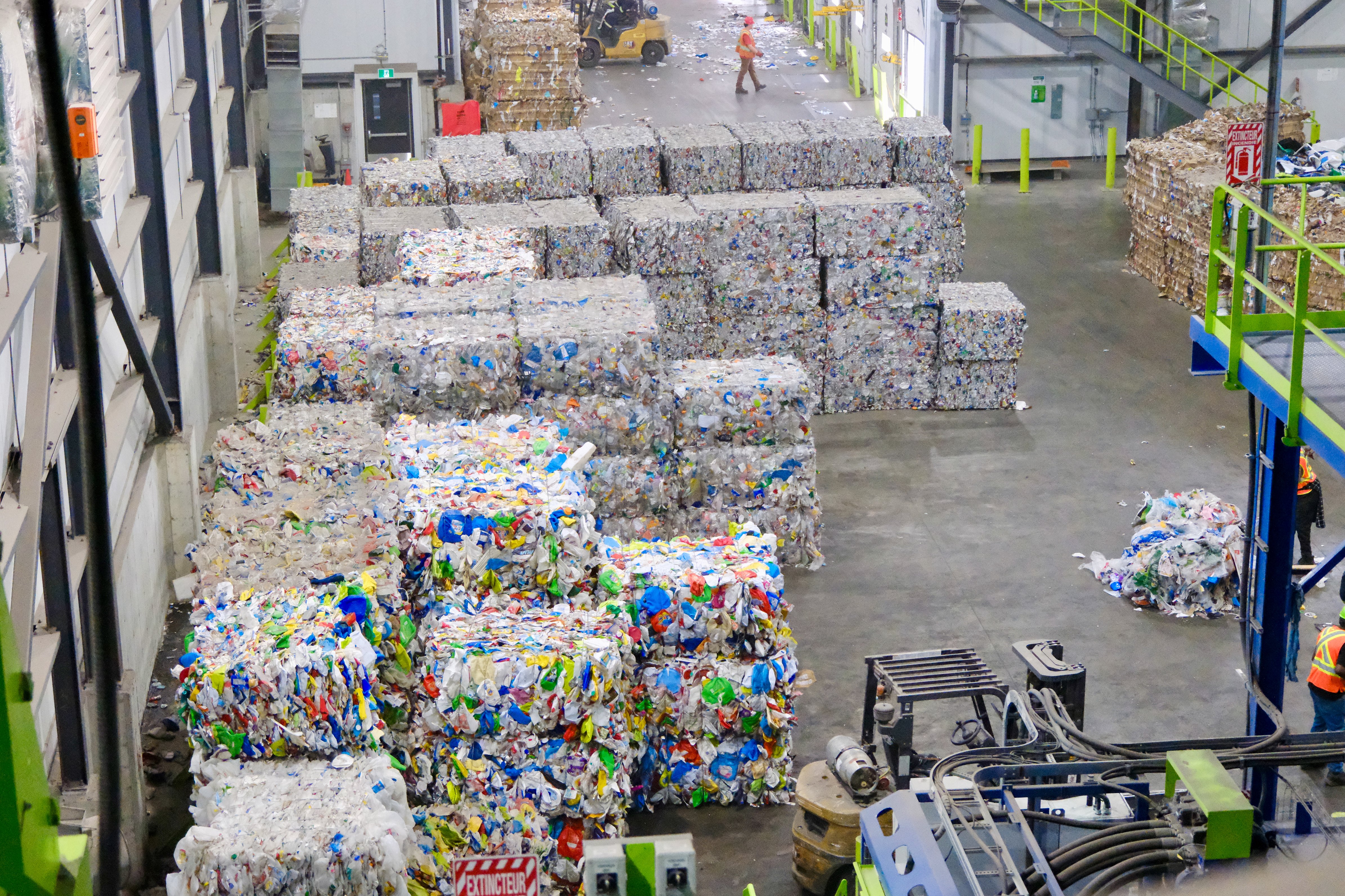 Rows of baled recovered plastic stacked across a sorting facility floor