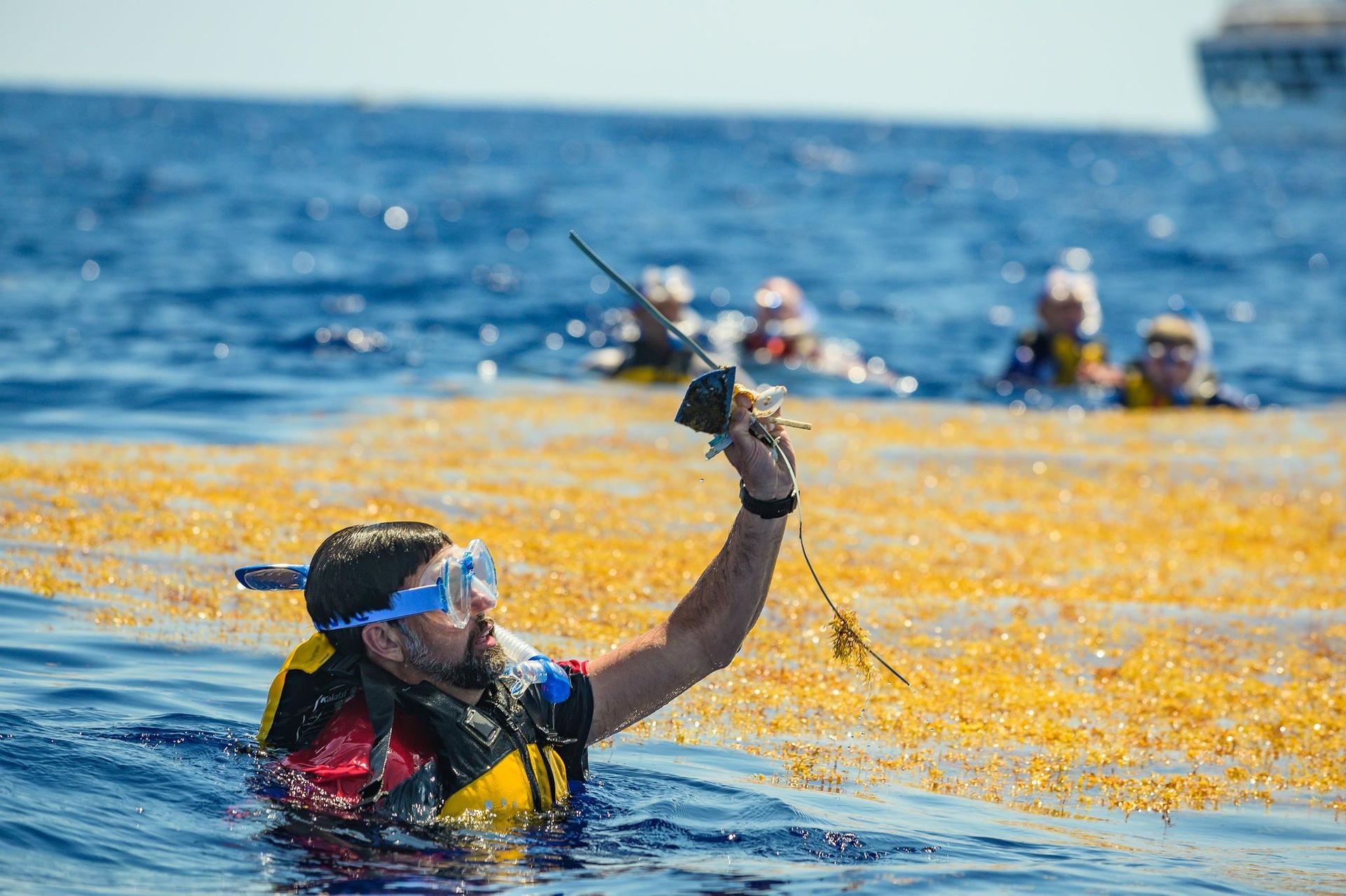 An expedition member holding up plastic debris recovered at sea