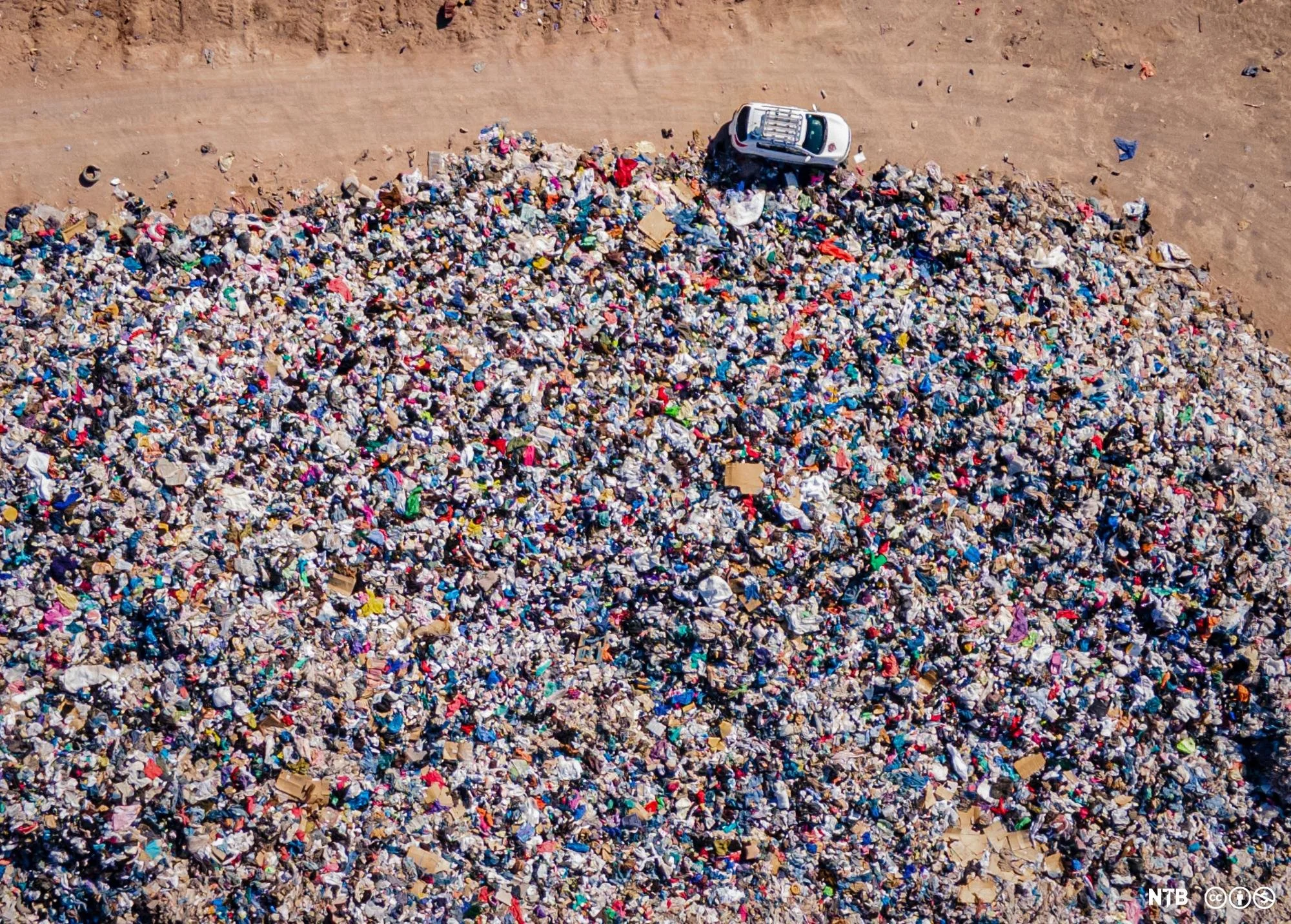 Aerial view of a vast pile of discarded clothing in the Atacama Desert near Alto Hospicio