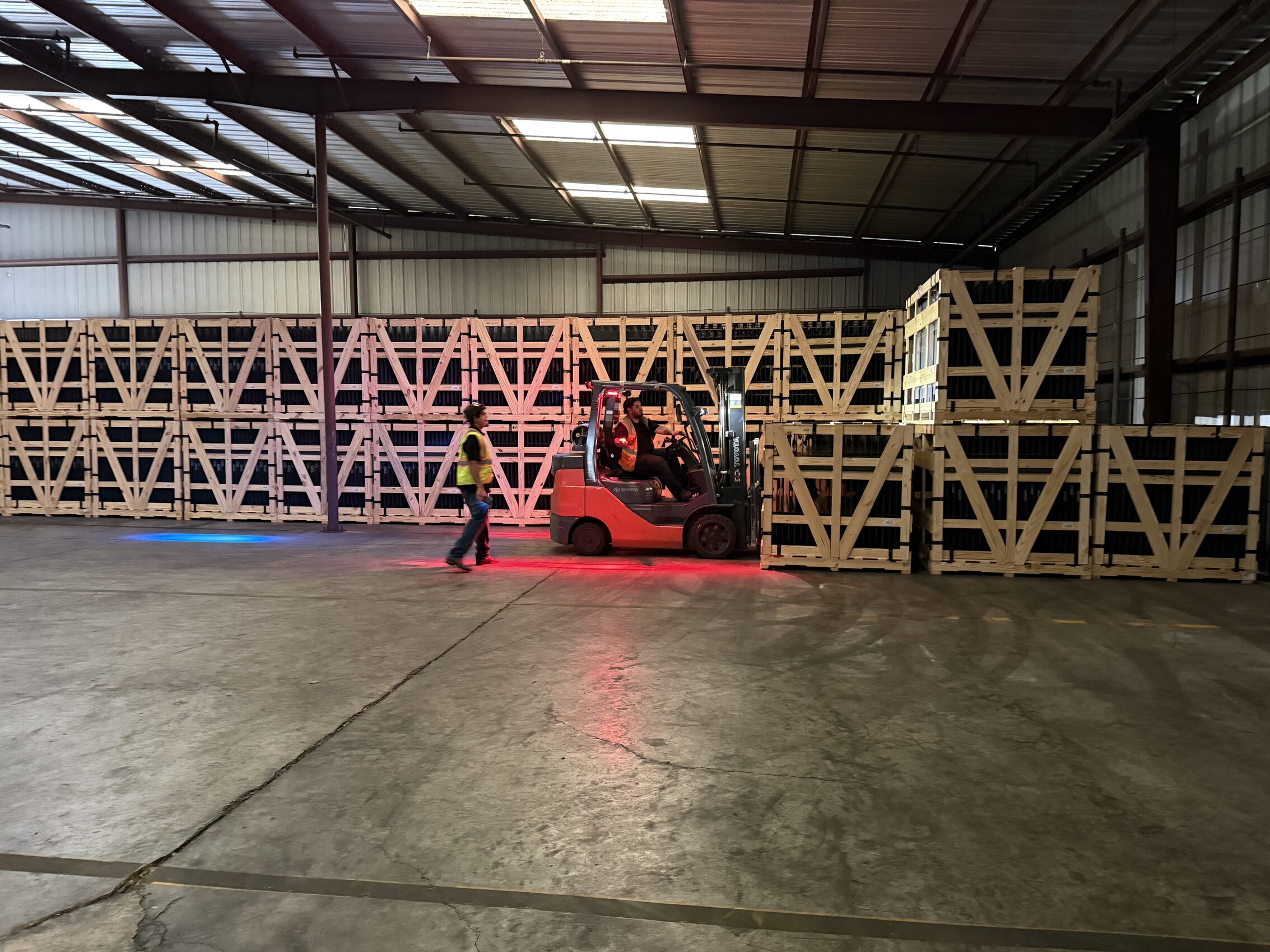 Forklift operator unloading crated solar panels inside Warehouse4Rent facility
