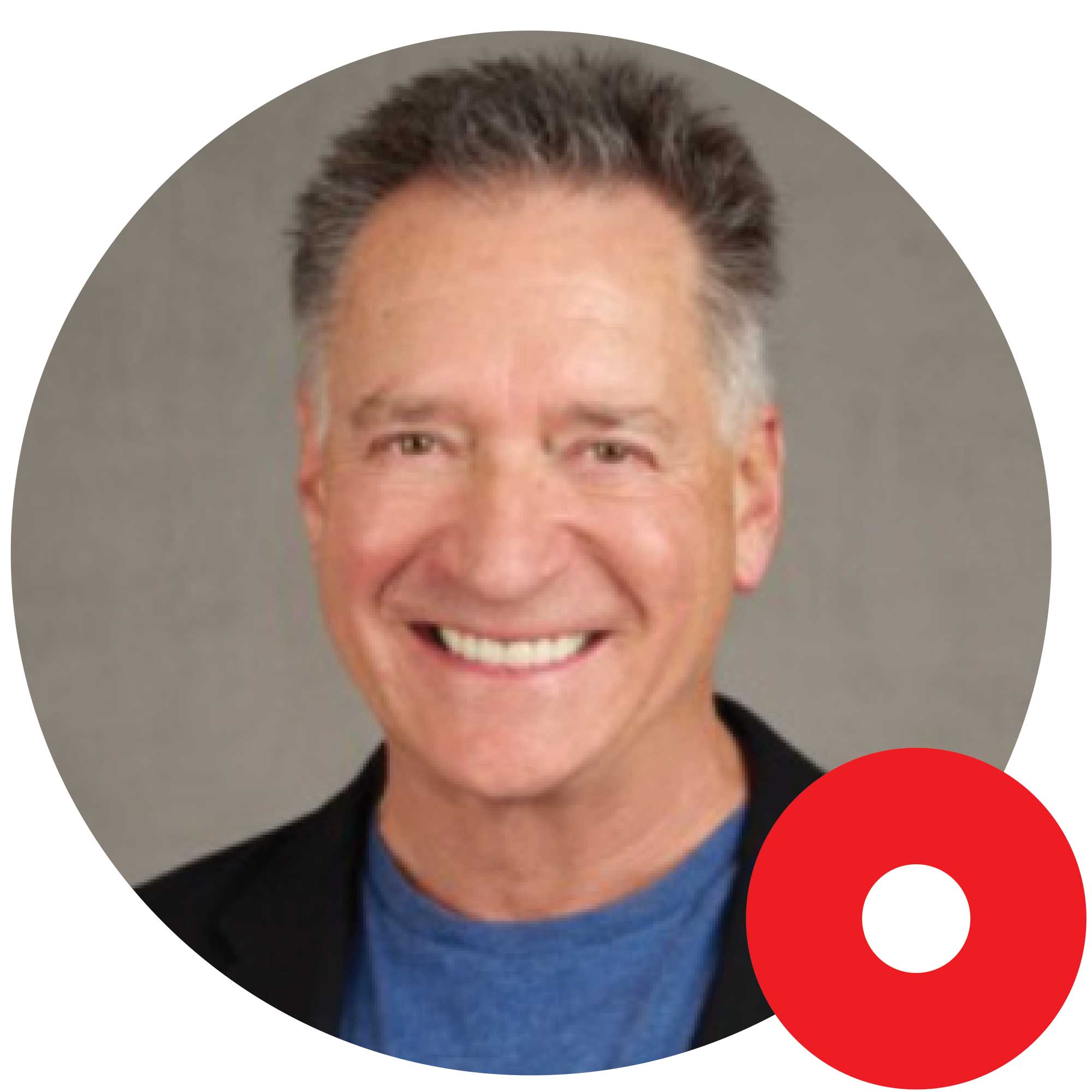 Smiling middle-aged man with short gray hair wearing a blue shirt and black blazer on a gray background.