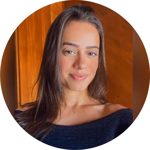 Mulher jovem com cabelos longos e lisos, usando blusa preta e sorrindo levemente, fundo de madeira.