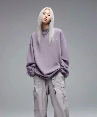 Young woman with long white hair wearing a loose lavender sweatshirt and light gray cargo pants.