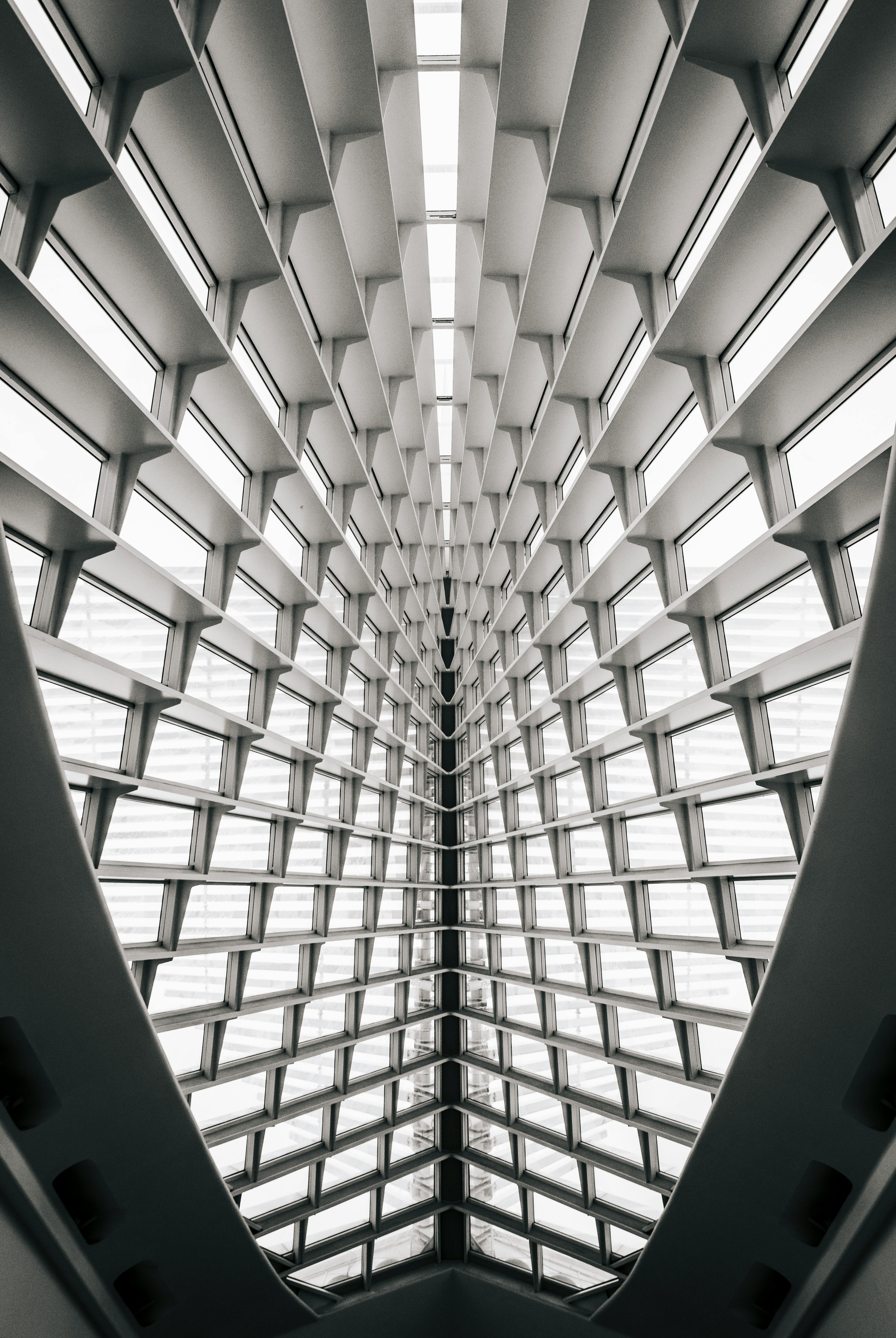Symmetrical interior view of a modern building ceiling with repetitive triangular window patterns converging to a central point.