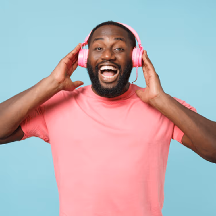 Homme souriant portant un t-shirt rose et des écouteurs roses, sur fond bleu clair.