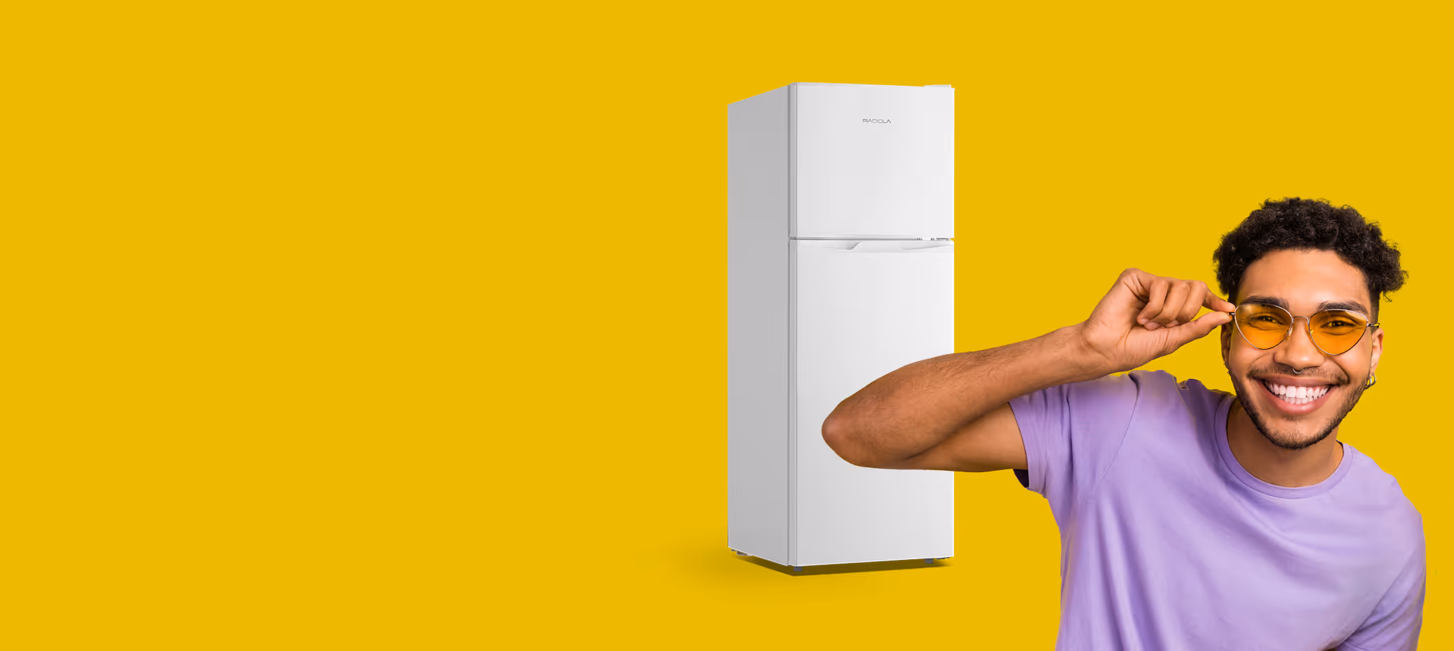 Jeune homme souriant portant des lunettes de soleil jaunes et un t-shirt violet, avec un réfrigérateur blanc en arrière-plan sur fond jaune.