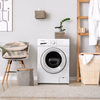 Machine à laver blanche dans une buanderie moderne avec un panier à linge, une chaise tapissée et des étagères en bois clair.