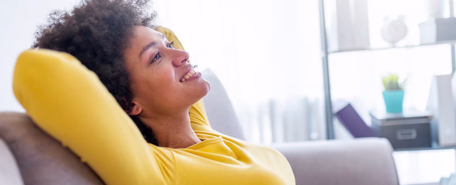 Happy and anxiety-free perimenopausal woman leaning on a sofa