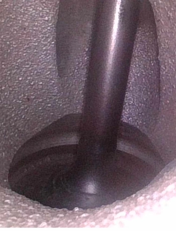 Close-up view of a clean engine intake valve inside the cylinder head.