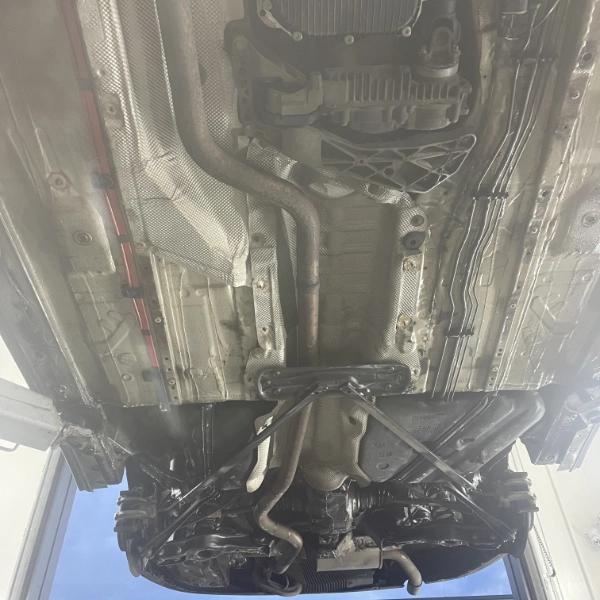 View of the underside of a car showing the exhaust system, heat shields, and chassis components.