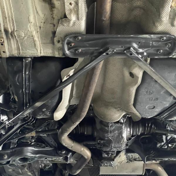 Underside of a vehicle showing metal exhaust pipes, heat shields, and structural components.