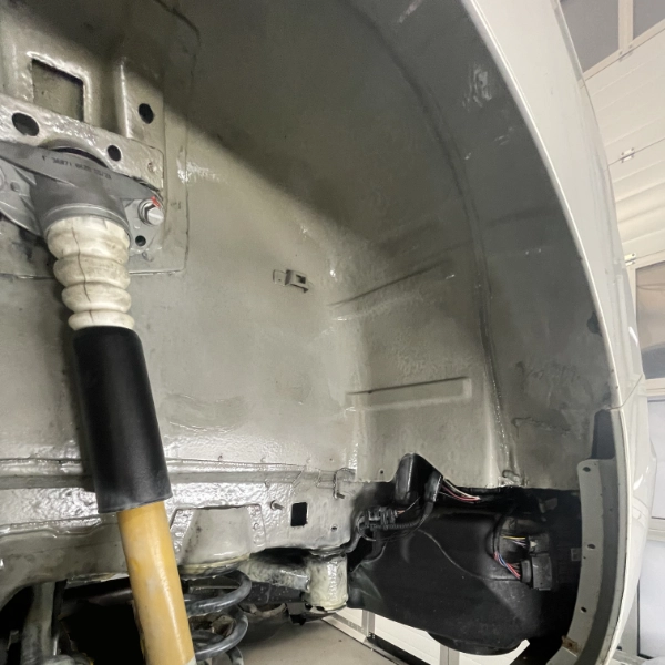 Close-up of a car's wheel well showing a sealed underbody with suspension components and wiring.