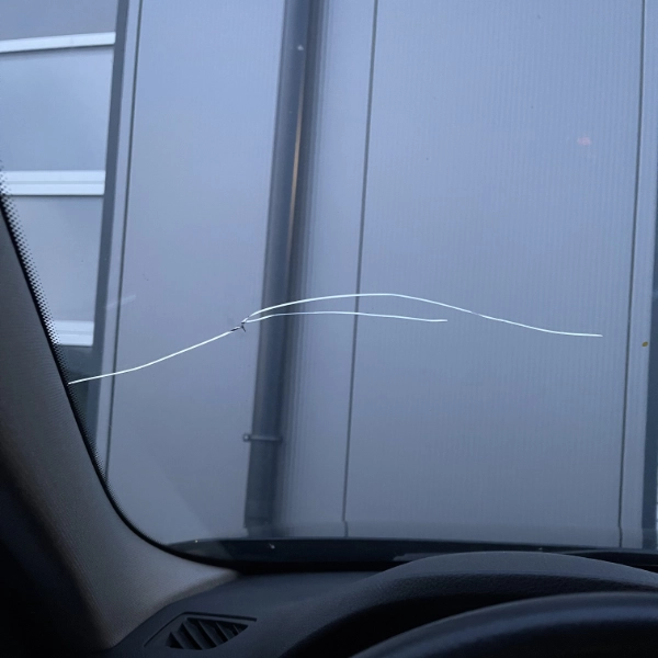 Crack running horizontally across a car windshield viewed from inside the vehicle.
