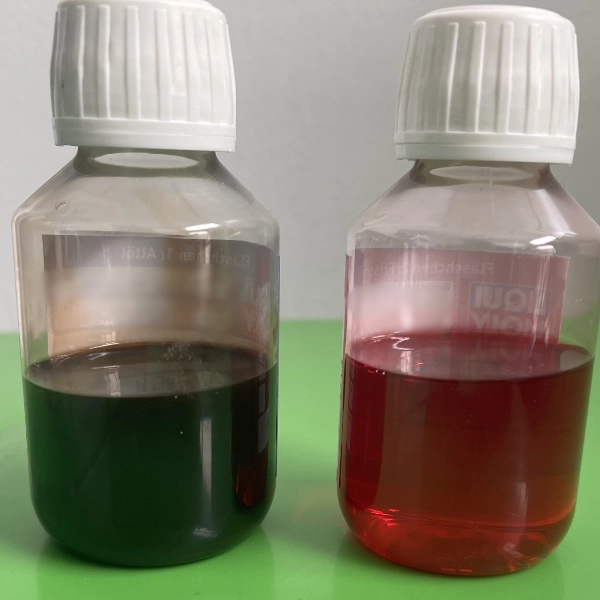 Two clear plastic bottles with white caps containing dark and reddish liquids placed on a green surface.