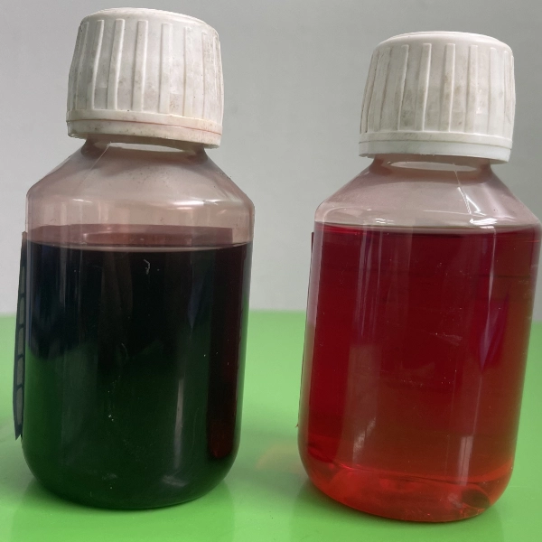 Two plastic bottles with white caps containing dark liquids, one dark purple and one red, placed on a green surface.