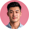 Portrait of a young East Asian man with short black hair wearing a blue shirt, smiling against a pink background.