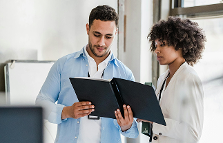 Man and woman reviewing documents together in a bright office space.