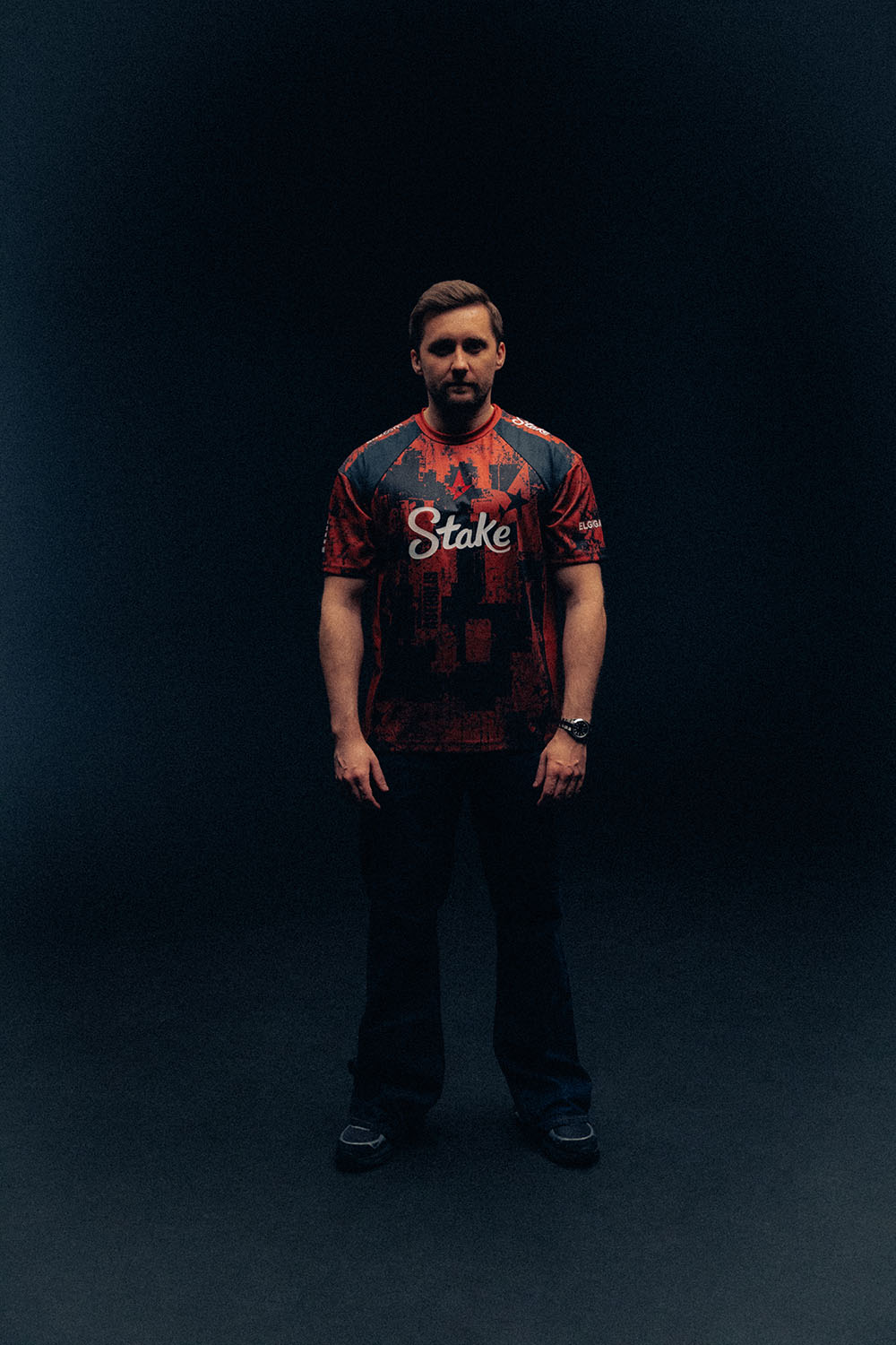 HooXi standing in a red and black Astralis jersey with his arms at his sides.