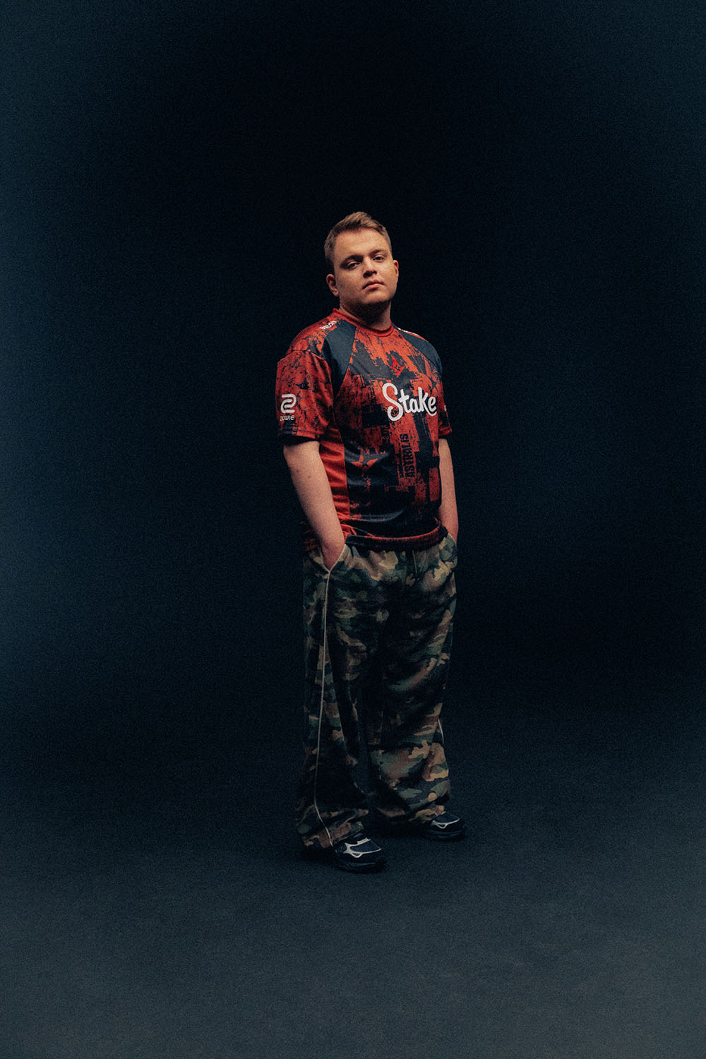 Ryu wearing an Astralis jersey and camouflage trousers with his hands in his pockets.