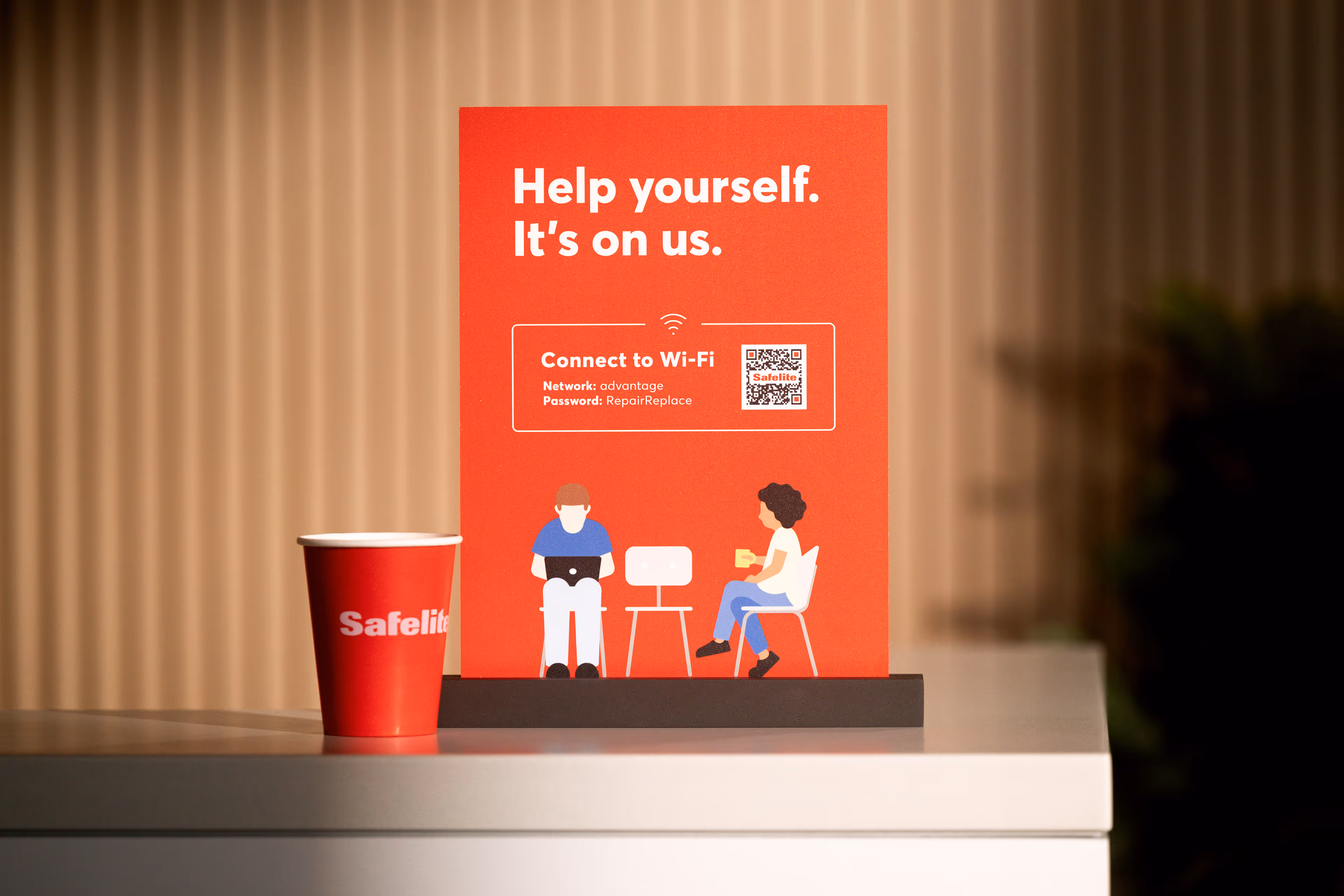 Red coffee cup with Safelite logo next to a red sign offering free Wi-Fi with network name advantage and password RepairReplace