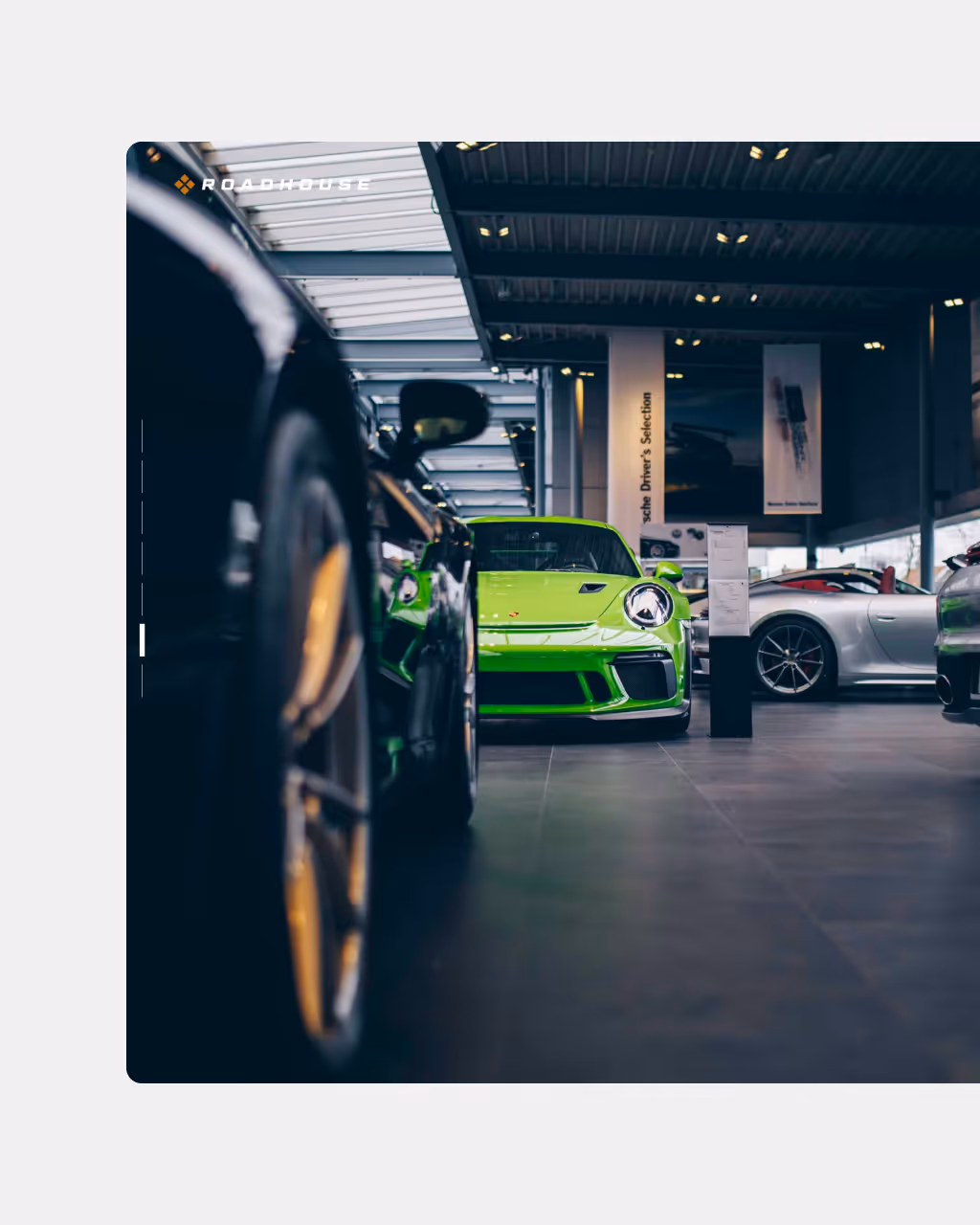 Green Porsche sports car displayed in a modern indoor showroom with other luxury cars.