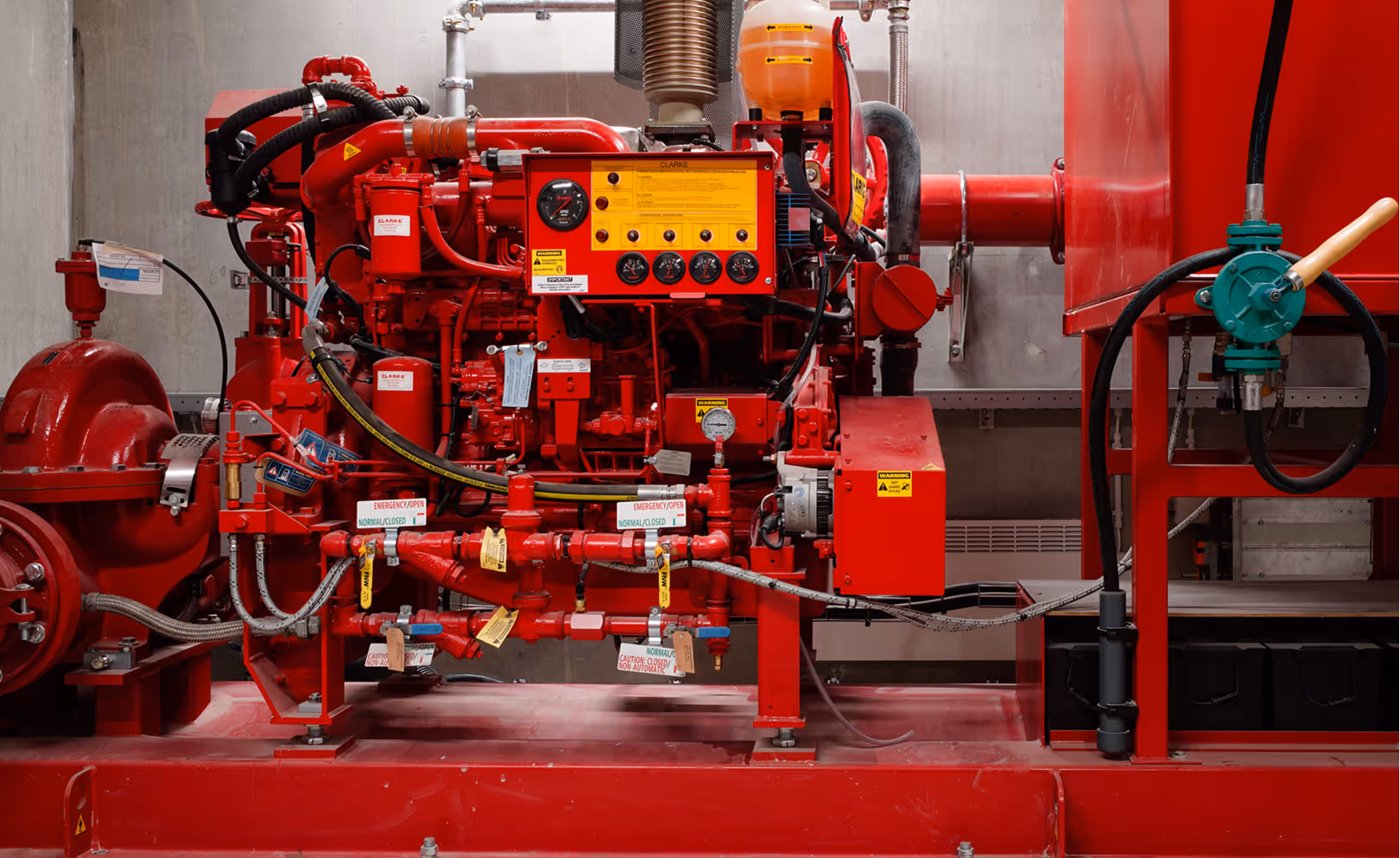 Red industrial fire pump system with gauges, valves, and pipes installed in a utility room.