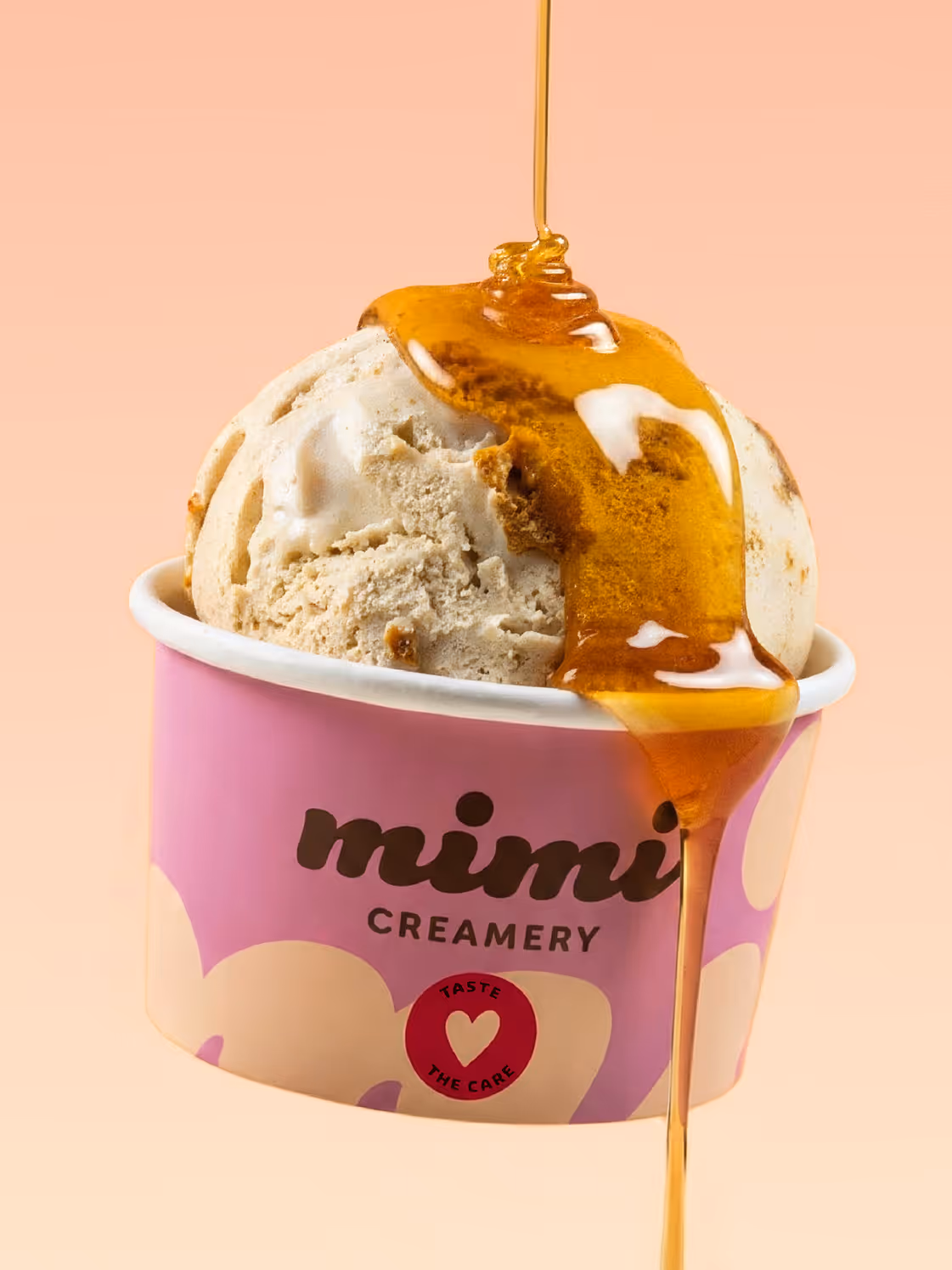 Scoops of ice cream with honey drizzle in a purple Mimi Creamery cup on a peach background.