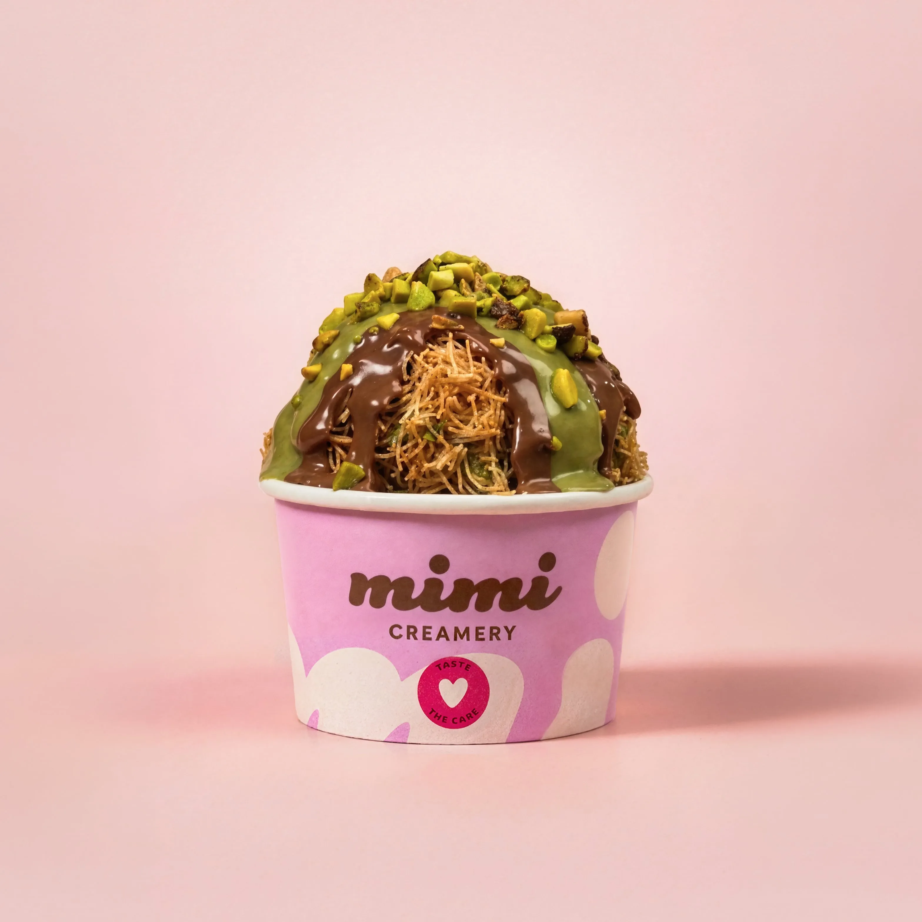 Mimi Creamery cup with rolled ice cream topped with chocolate, green sauce, and chopped nuts.
