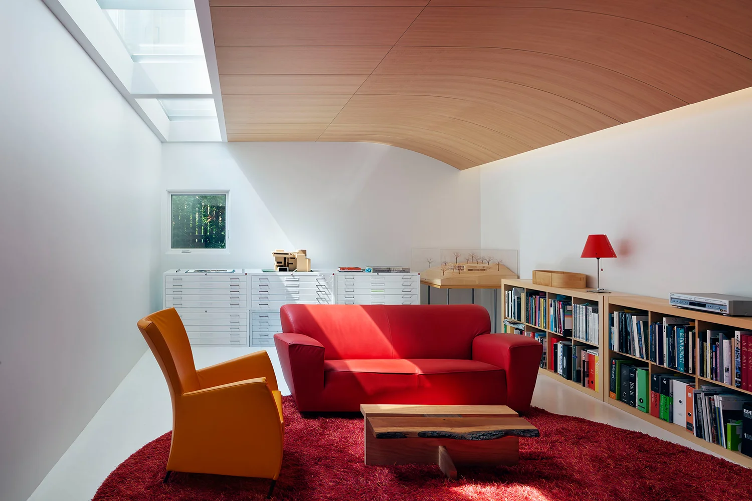 A basement family room with curved wood ceiling for indirect light, and a glass ceiling to borrow natural light from above.