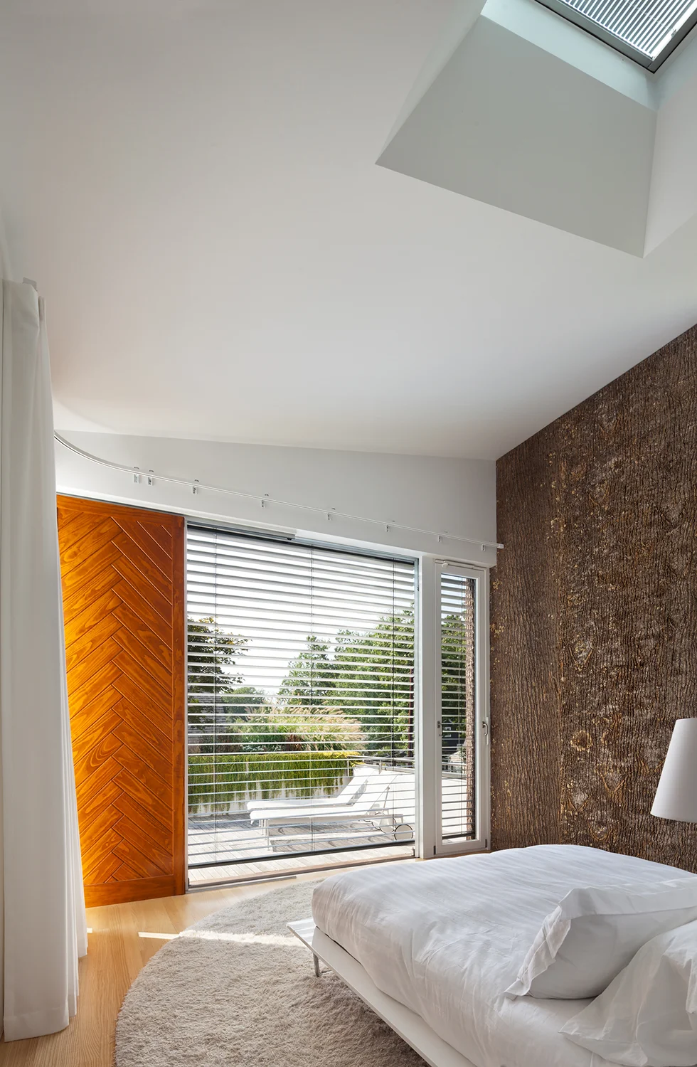 The primary bedroom looking out through a 10x10 foot glass wall to the 2nd story deck.