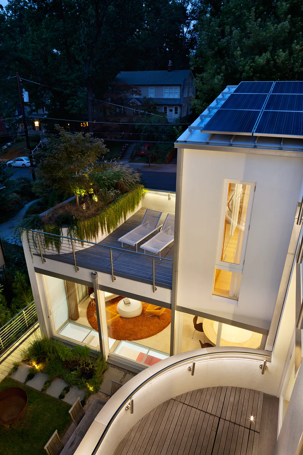 Two views of the living room with primary deck above and the rear courtyard, from the courtyard and from the upper roof looking down.