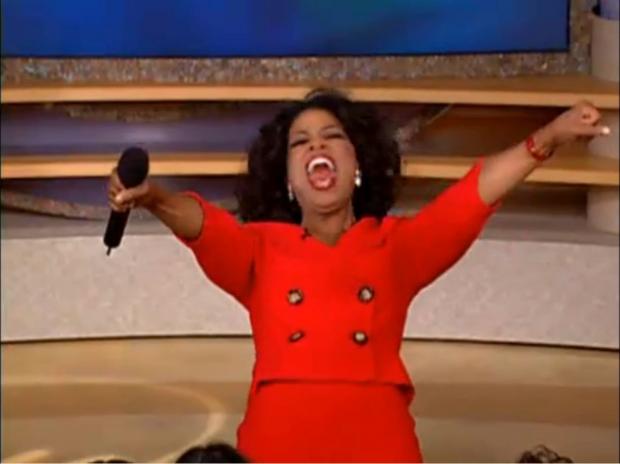 An image of an excited Oprah Winfrey yelling with arms extended
