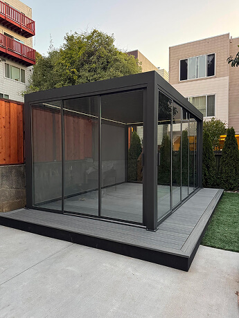 Fully enclosed aluminum pergola with panoramic sliding glass walls for year-round outdoor living in Bay Area, California.