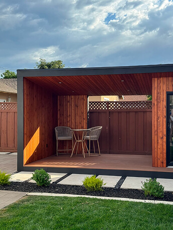 Custom modern solid patio cover with cedar walls and ceiling, creating a cozy outdoor seating area in a California backyard.