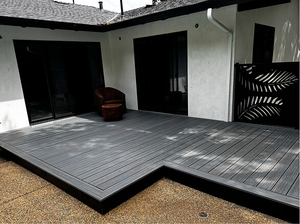 Modern gray composite deck with integrated steps installed in a residential backyard