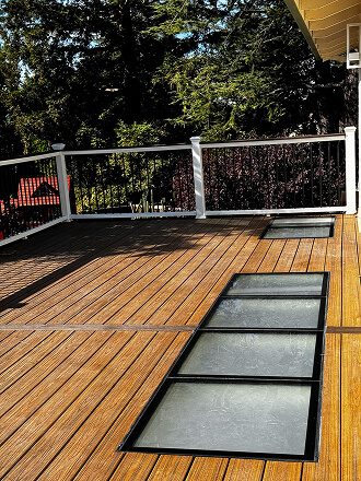 Custom wood deck with integrated glass floor panels and modern cable railing