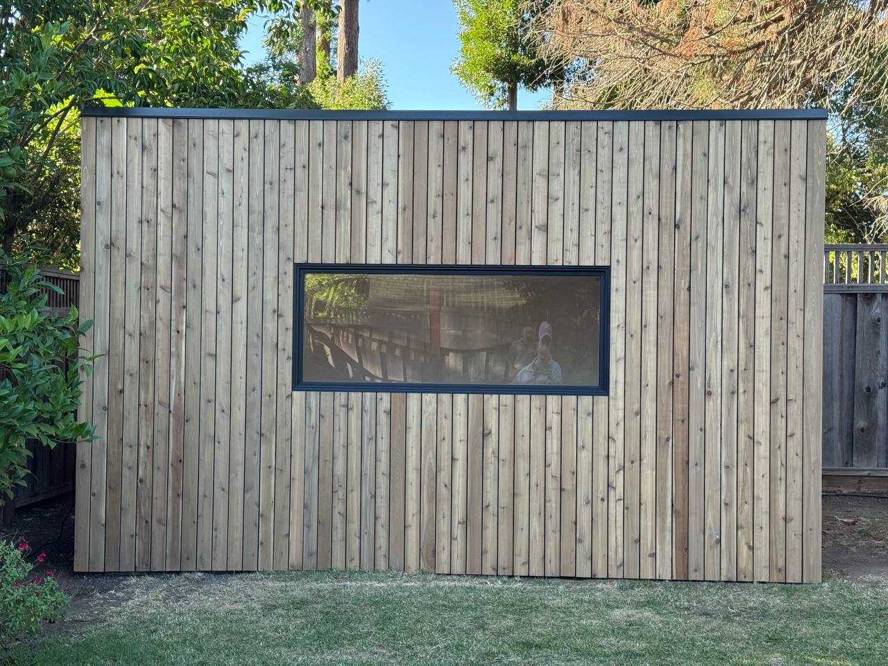 Side view of the Modern Cube backyard studio featuring cedar cladding and a large horizontal window