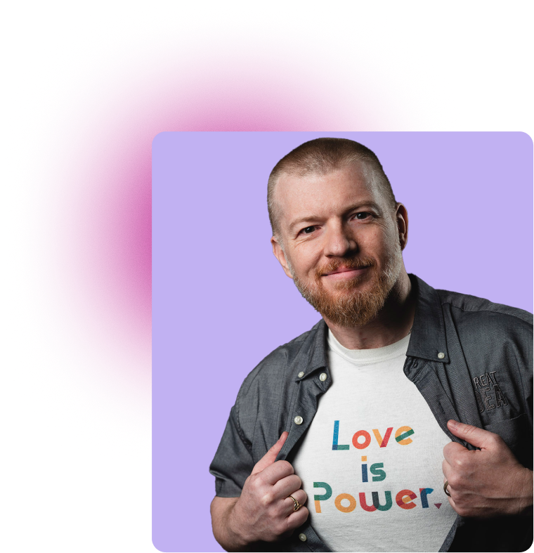 Smiling man with short hair and beard showing a white T-shirt that reads 'Love is Power' in colorful letters.