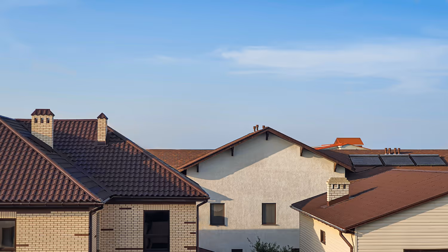 Roofs of residential houses under clear blue sky in daylight.