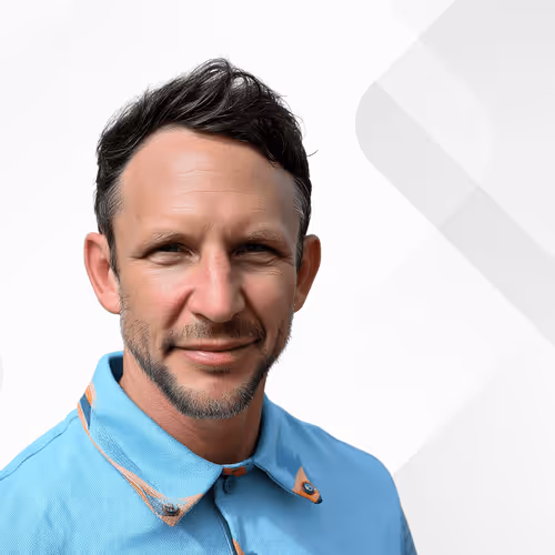 Portrait of a middle-aged man with short dark hair and a beard wearing a light blue collared shirt.